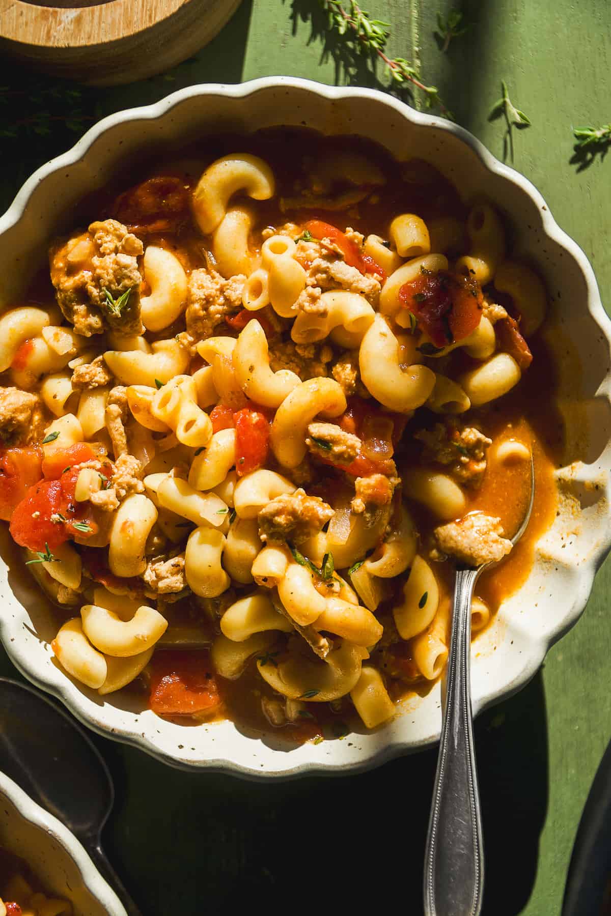 Macaroni tomato soup with ground turkey in a bowl with a spoon.