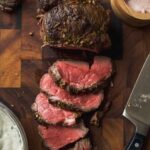 Slices of beef tenderloin on a wooden cutting board.