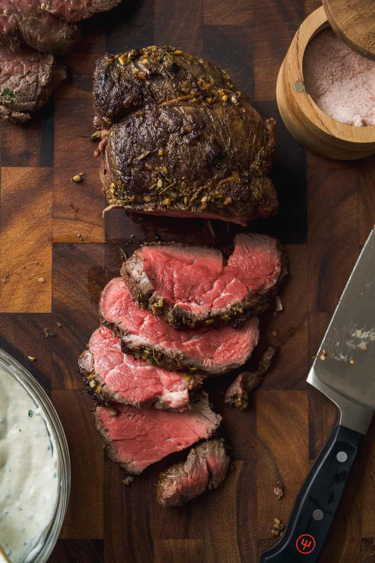 Slices of beef tenderloin on a wooden cutting board.