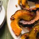 Acorn squash slices tossed in a maple pecan dressing roasted in the oven on a platter.