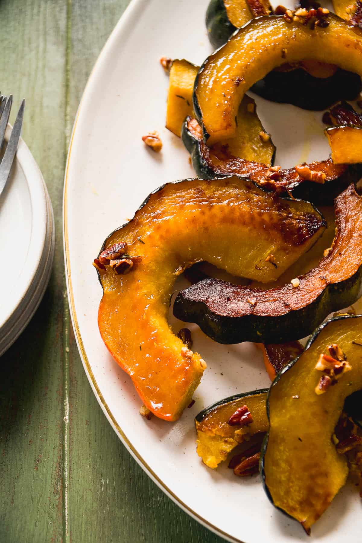Acorn squash slices tossed in a maple pecan dressing roasted in the oven on a platter.