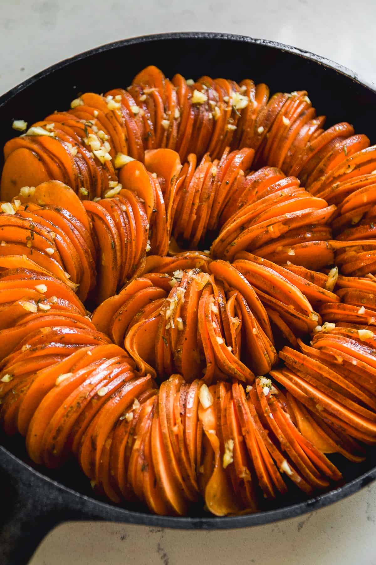 Sweet potatoes shaped into a large spiral in a cast iron skillet.