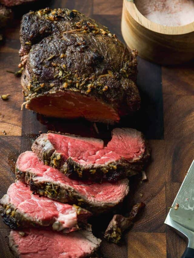 Beef tenderloin cut into slices on a cutting board.