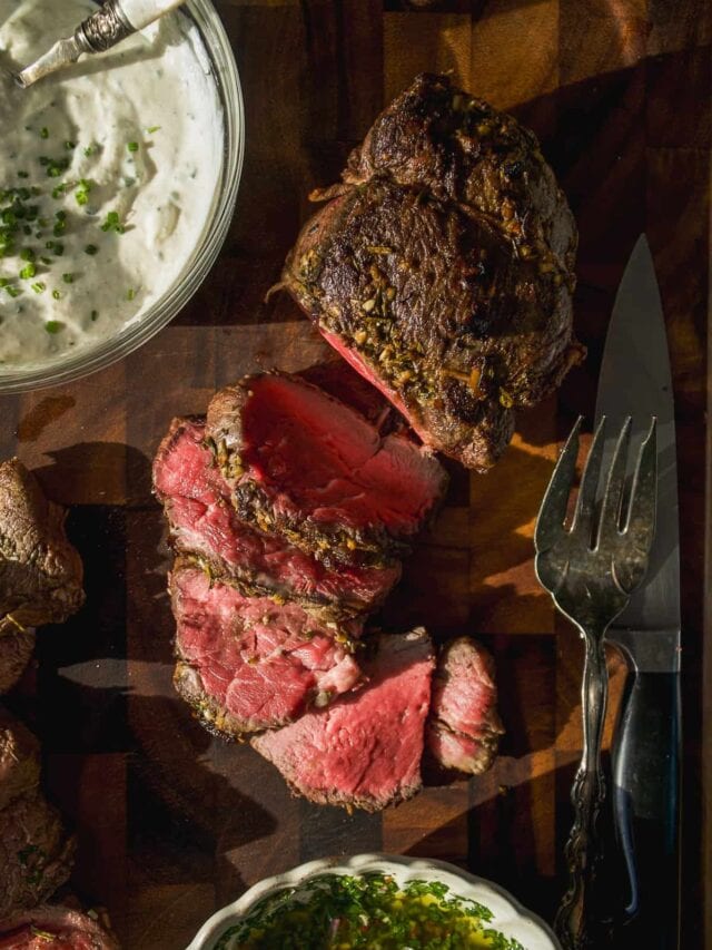 Beef tenderloin cut into slices on a cutting board with slices.