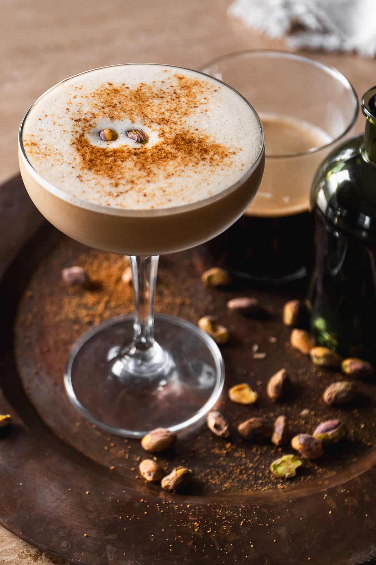 Baklava espresso martini in a glass with a few pistachios on top.