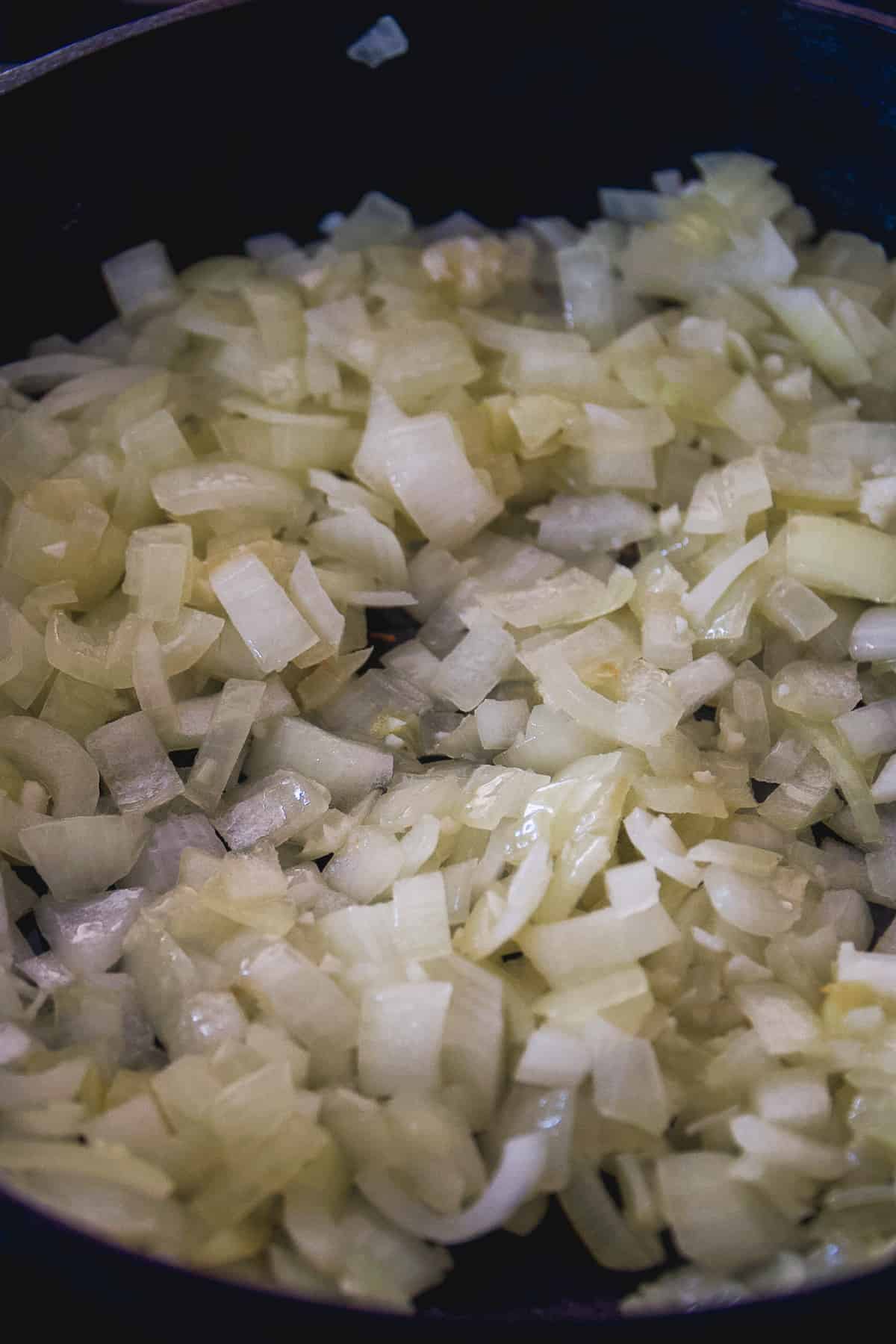 White onions being sauted in a skillet.