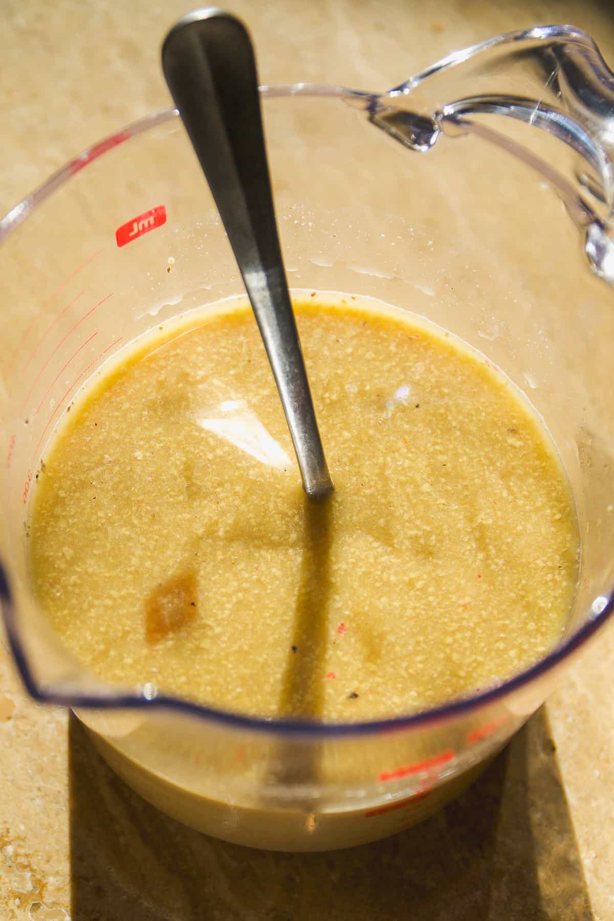 Beef stroganoff sauce in a measuring cup with a spoon.