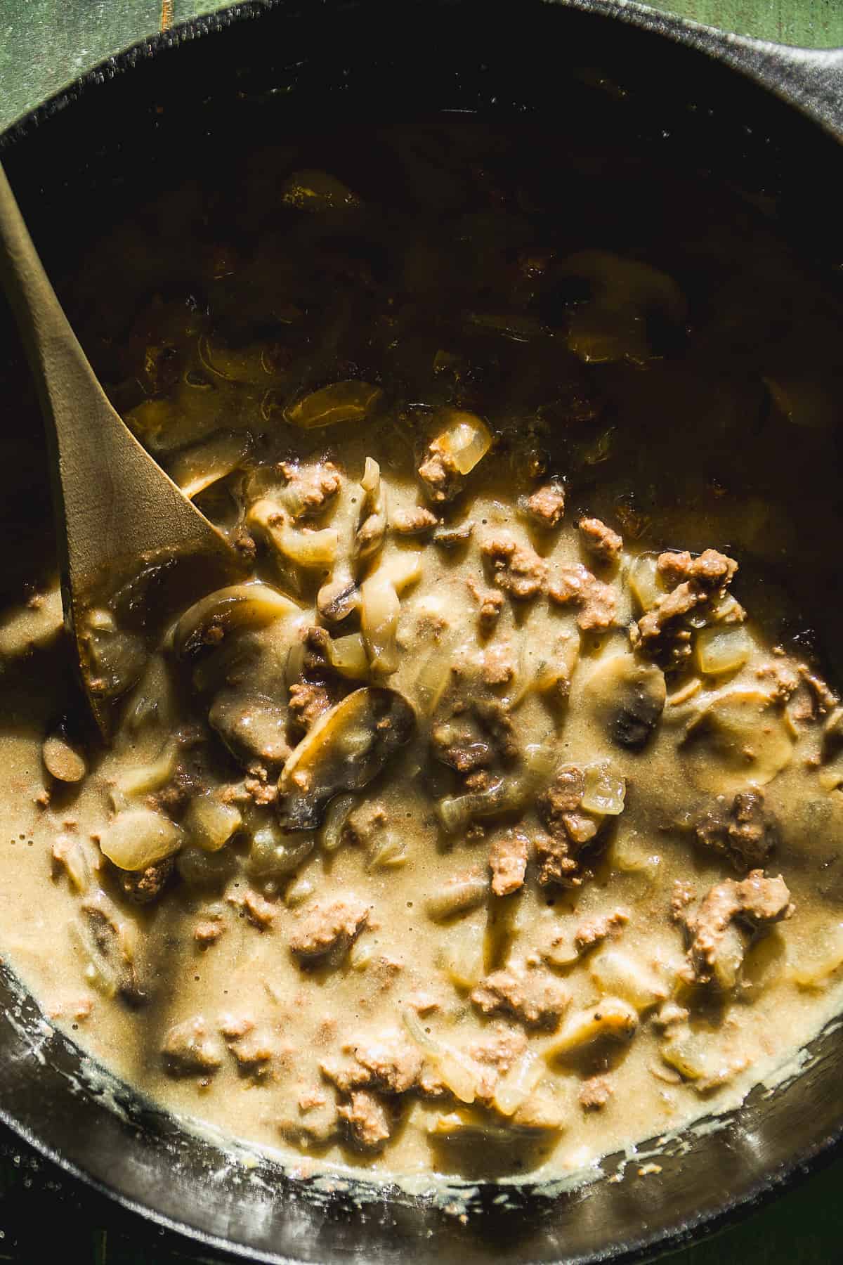 Beef stroganoff in a skillet with a wooden spoon.