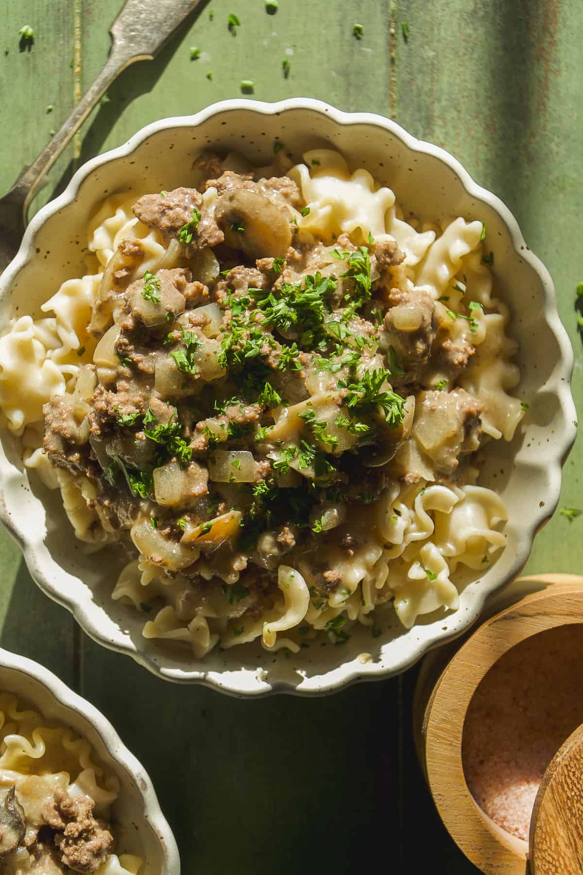 Beef stroganoff on top of pasta noodles in a bowl with a fork.