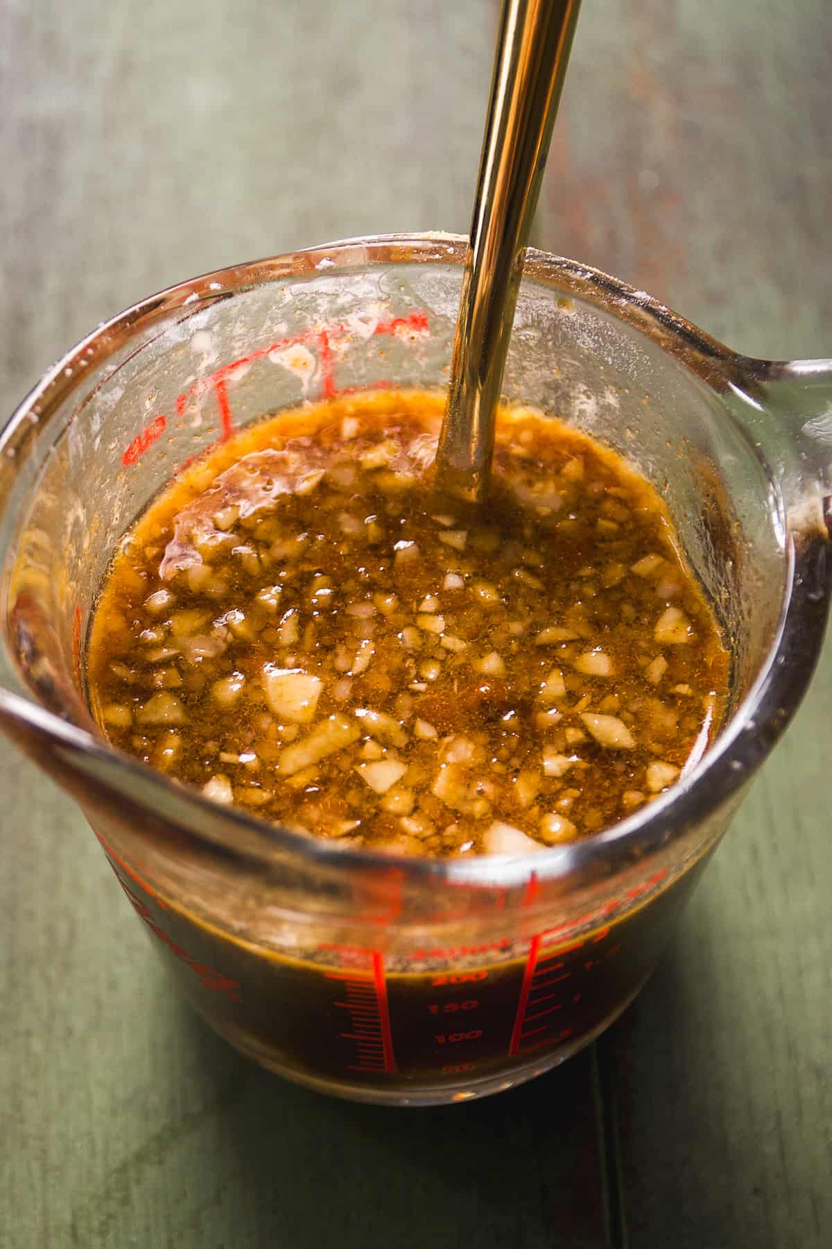 Teriyaki sauce with minced garlic in a measuring cup.