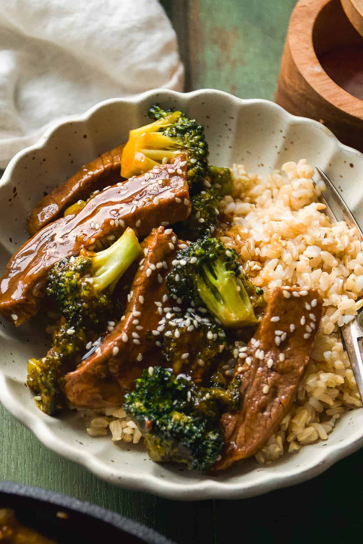 Beef and broccoli in a bowl with rice and sesame seeds.