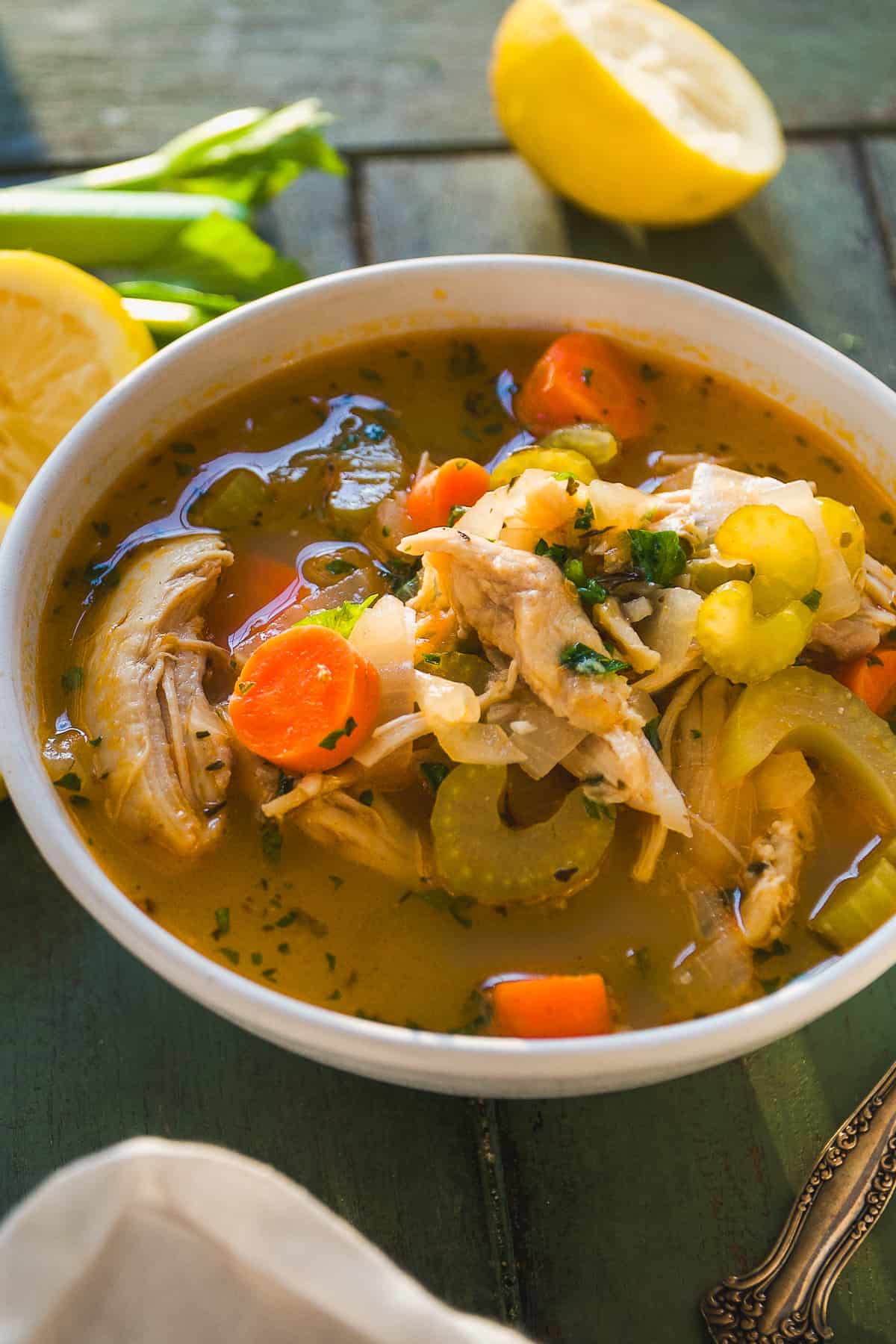 Chicken and veggie soup in a bowl with a spoon.