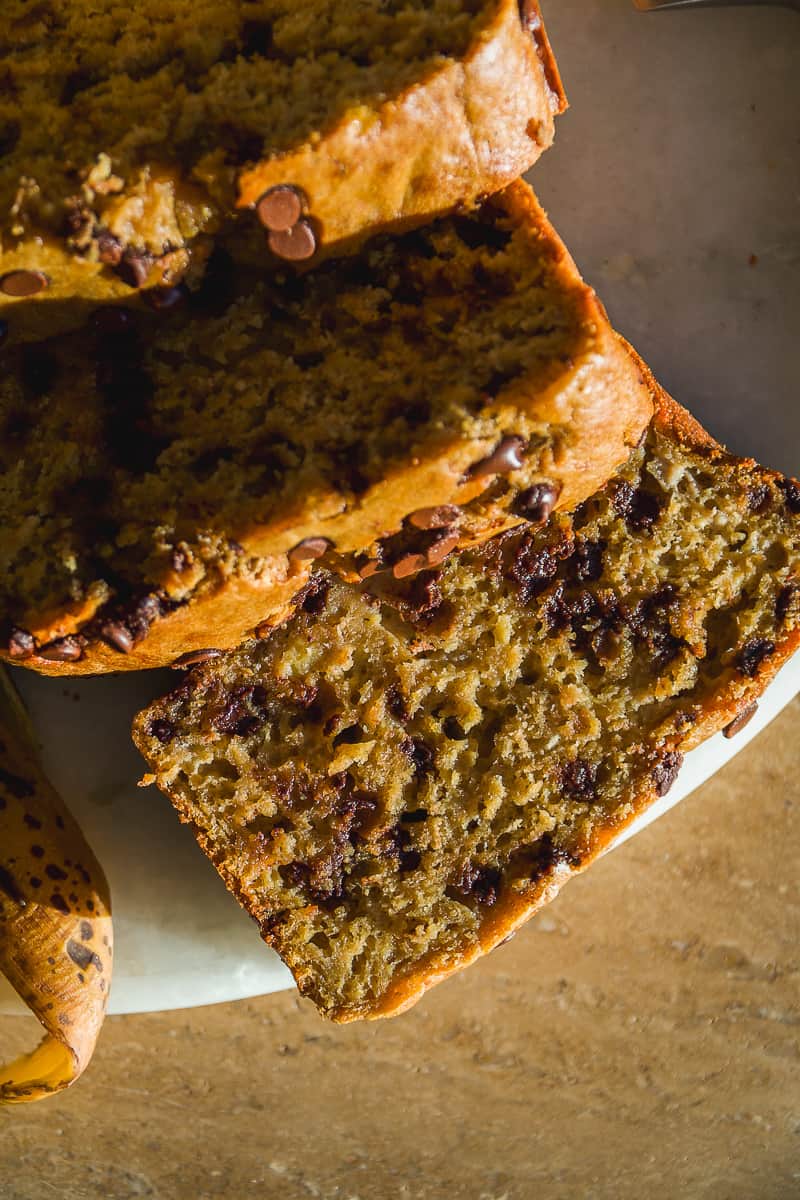 Oat flour banana bread with chocolate chips cut into slices on a platter.