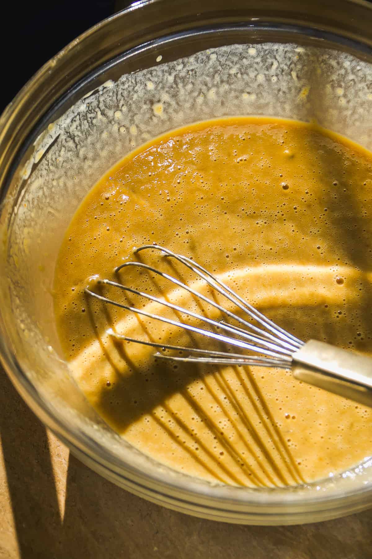 Wet ingredients in a bowl with a wisk.