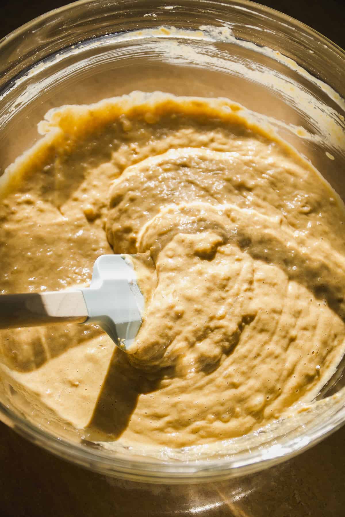 Oat flour banana bread batter being mixed in a glass bowl.