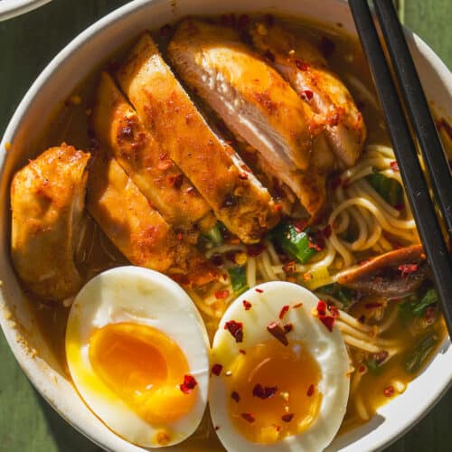 Overhead view of a bowl with chicken ramen noodles and a soft boiled egg.