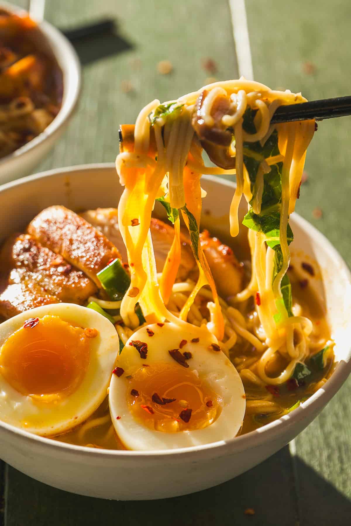 Ramen noodles being picked up with chopsticks.