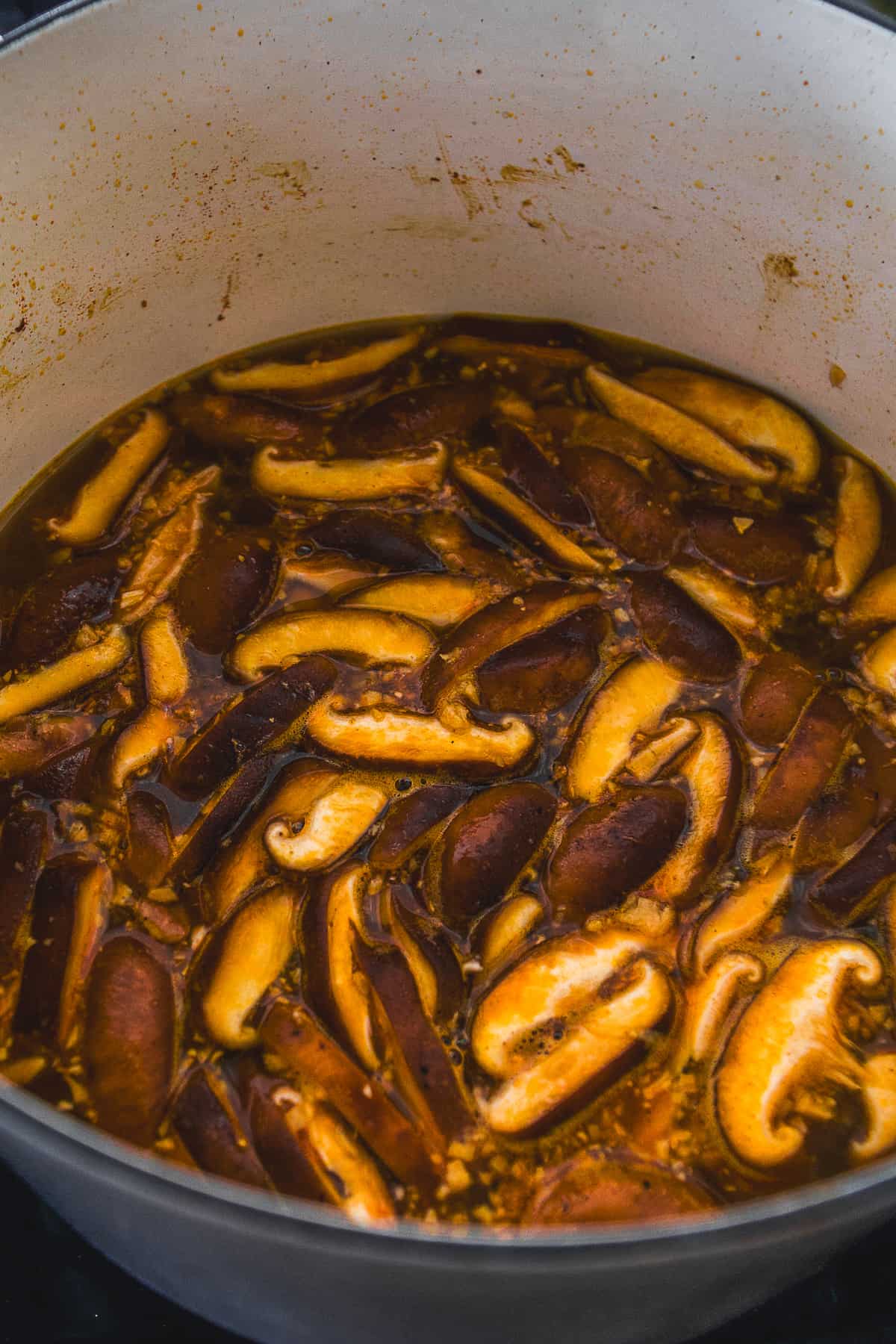 Mushrooms simmering in a pot with broth and spices.