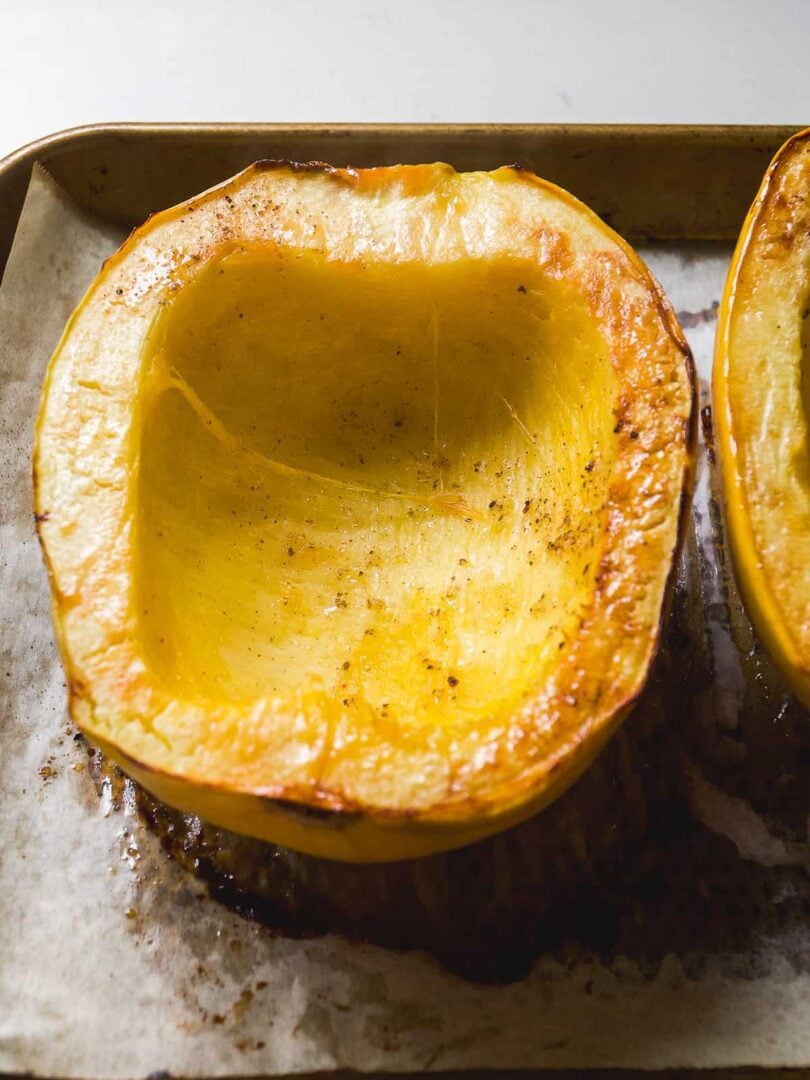 Roasted spaghetti squash halves on a baking pan.