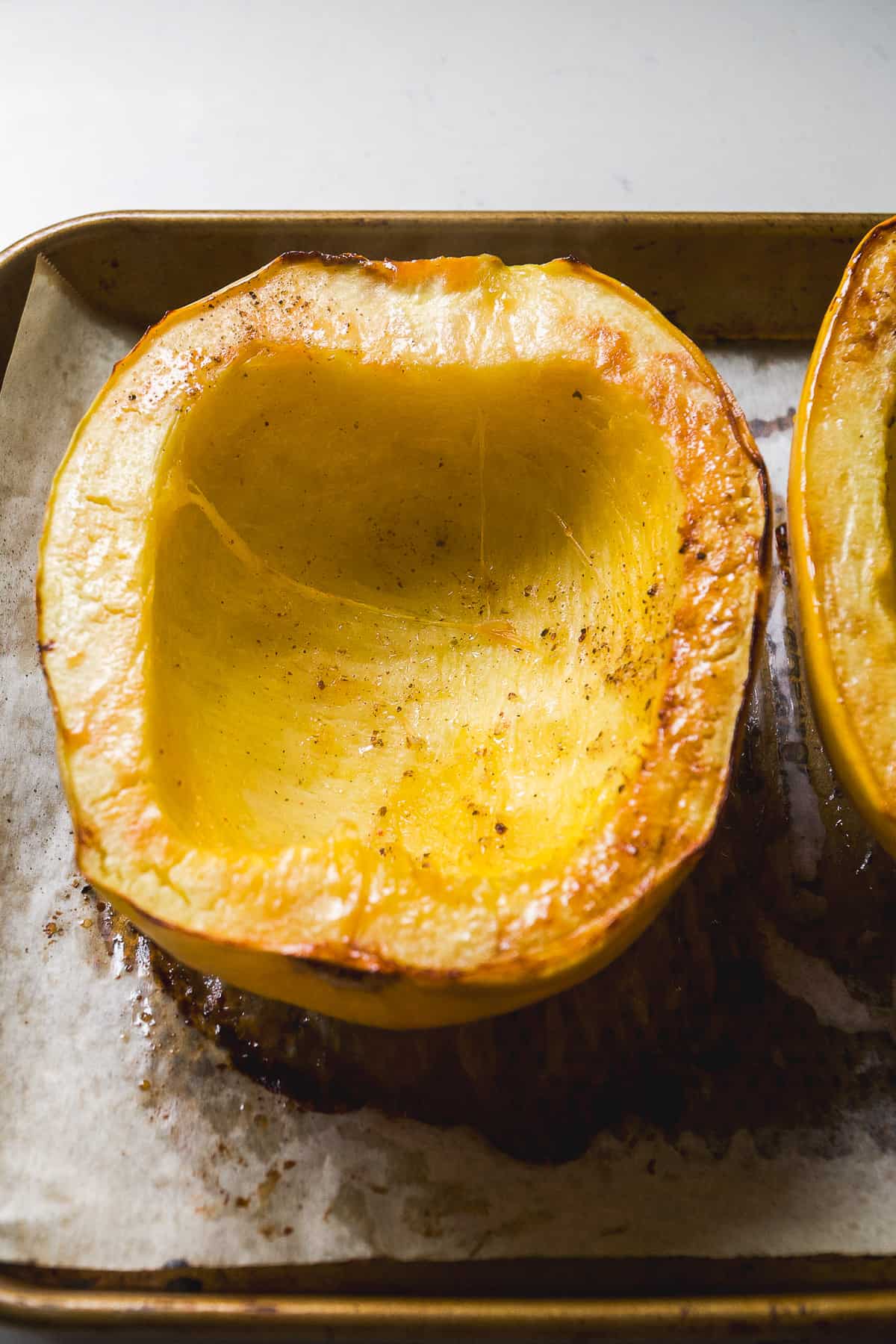 Roasted spaghetti squash halves on a baking pan.