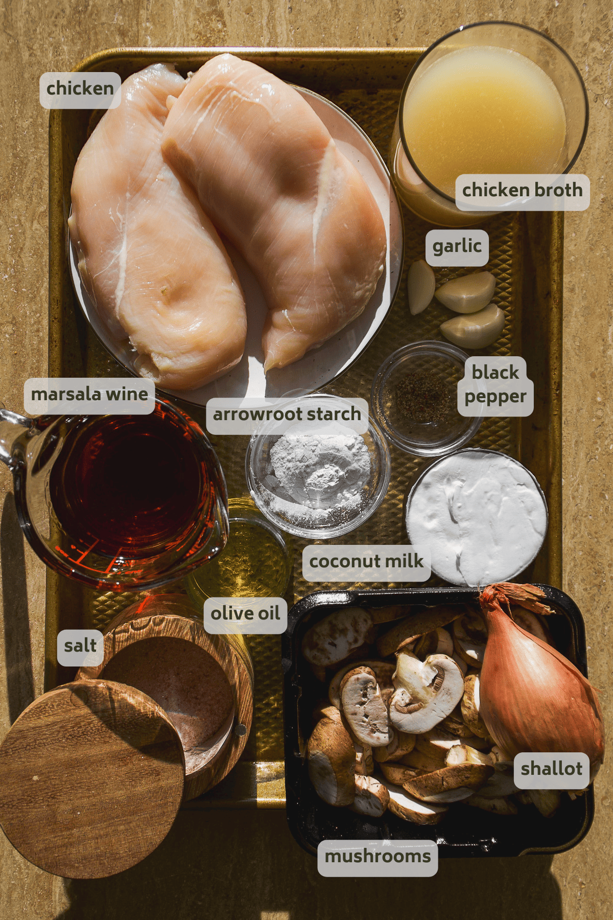 Chicken marsala ingredients on a gold baking sheet with labels.