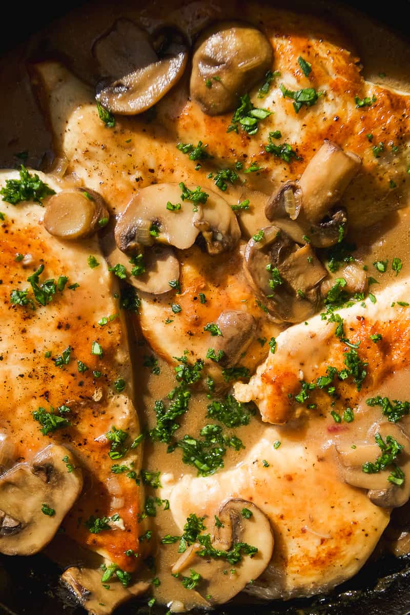 Chicken marsala with herbs and mushrooms in a skillet.