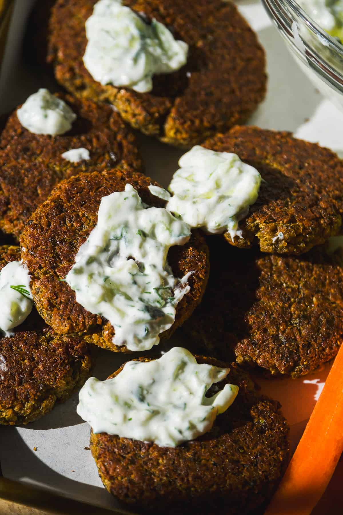 Baked falafel on a platter with tzatziki spread on top.