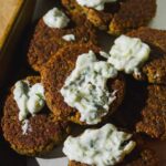 Baked falafel patties on a platter with tzatziki sauce.