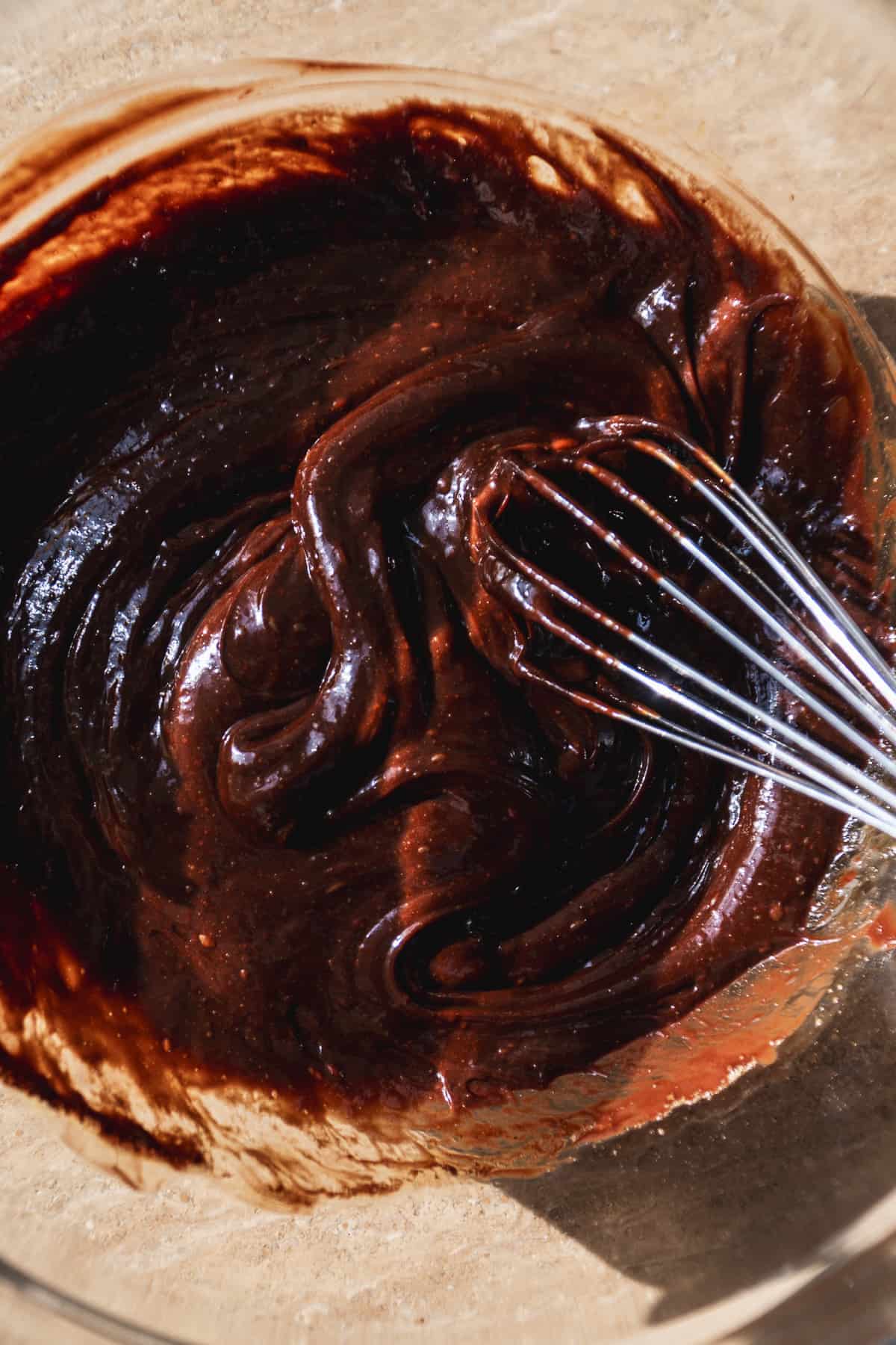 Chocolate flourless cake batter in a bowl with a whisk.