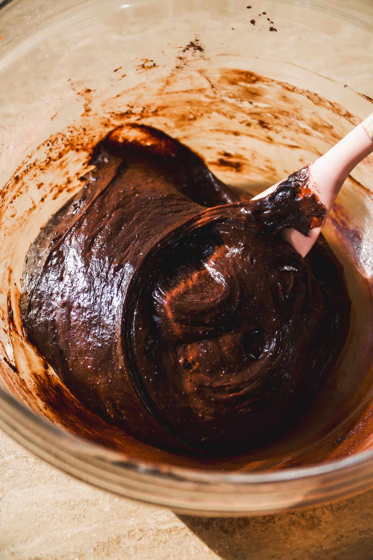 Flourless chocolate cake batter in a glass bowl with a spatula.
