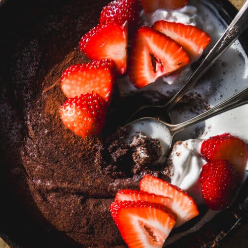 Overhead view of chocolate cast iron skillet cake with strawberries.