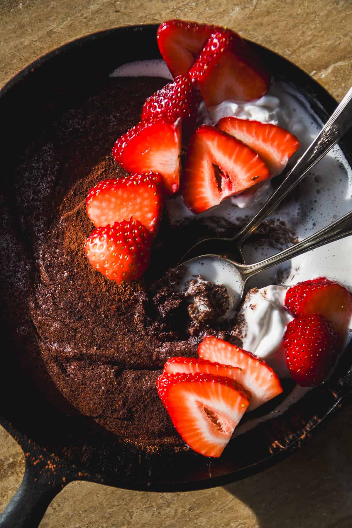 Overhead view of chocolate cast iron skillet cake with strawberries.