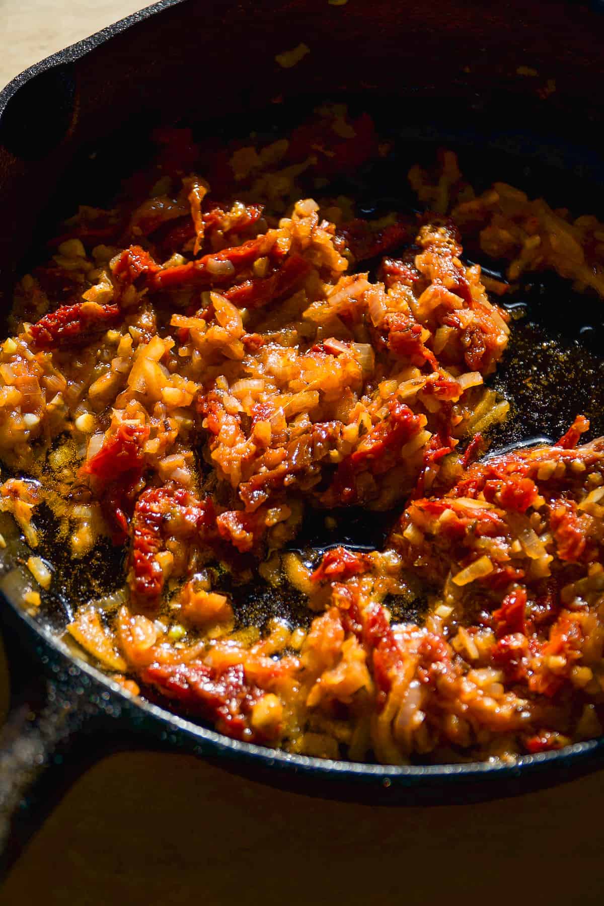 Sundried tomatoes mixed into shallots and garlic in a skillet.