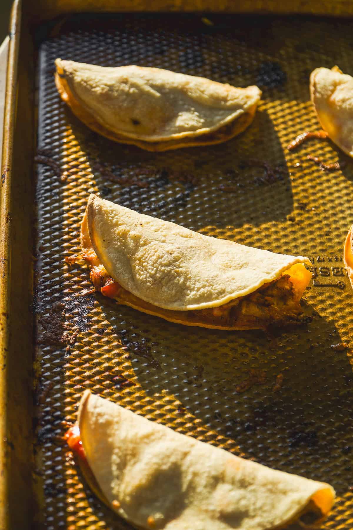 Crispy chicken tacos on a baking sheet.