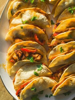 Baked chicken tacos on a platter with cilantro on top.