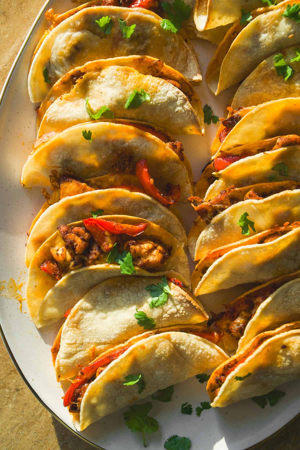 Baked chicken tacos on a platter with cilantro on top.