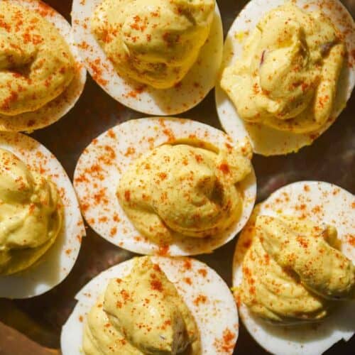 Greek yogurt deviled eggs on a platter with paprika.