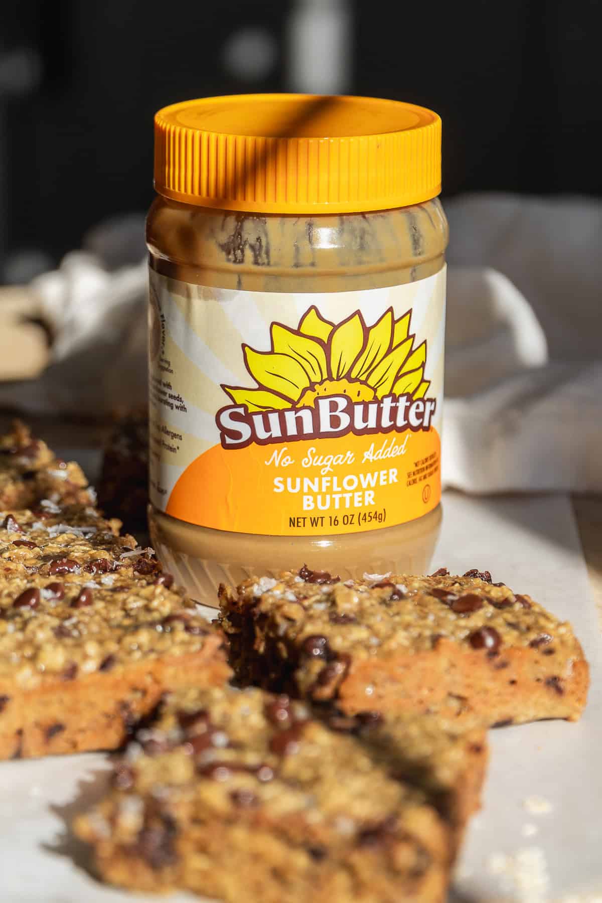 SunButter jar with oatmeal bars on surface.