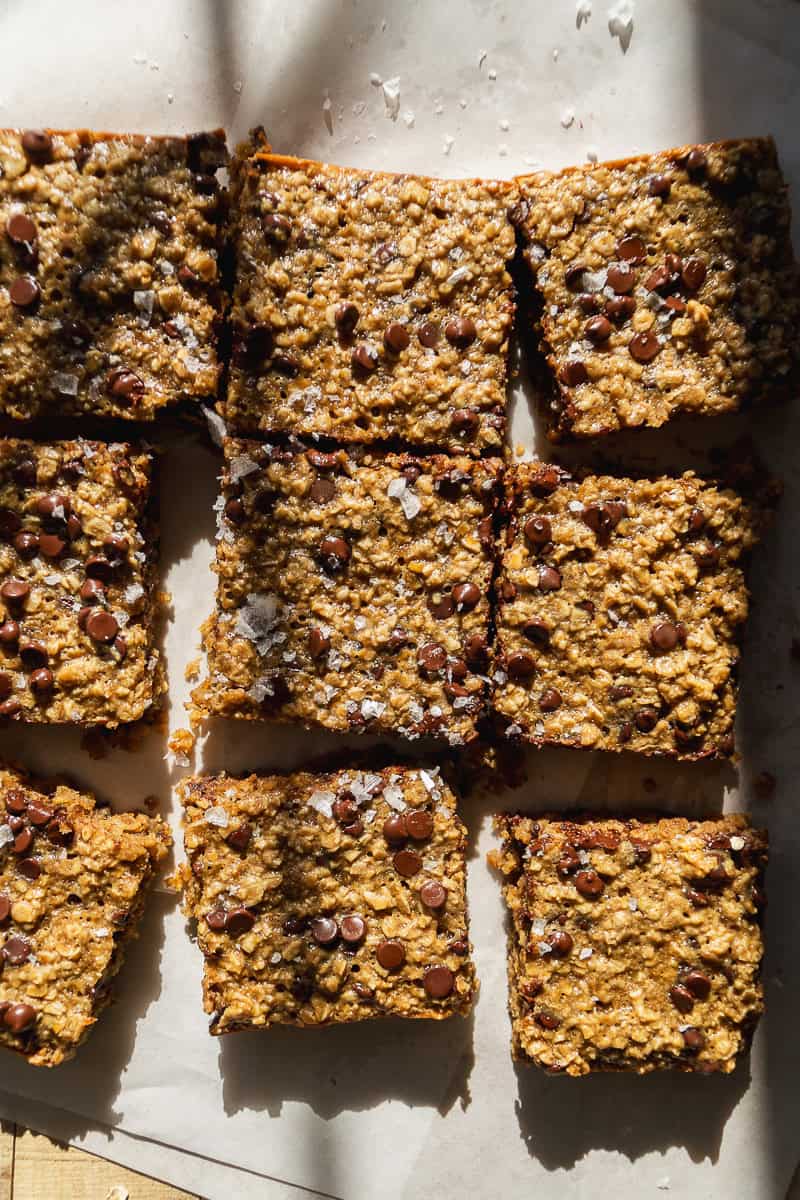 Oatmeal bars cut into squares on parchment paper.