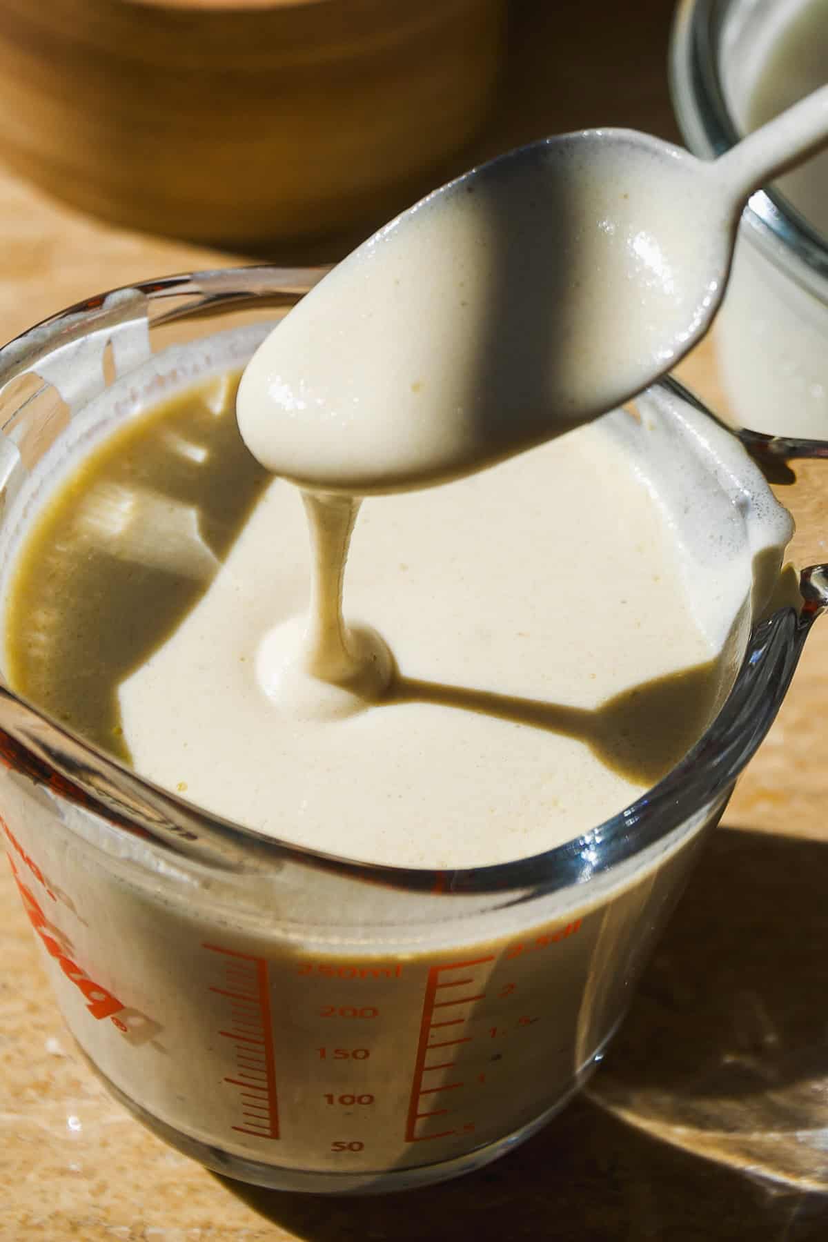 Creamy greek yogurt salad dressing in a measuring cup with a spoon.
