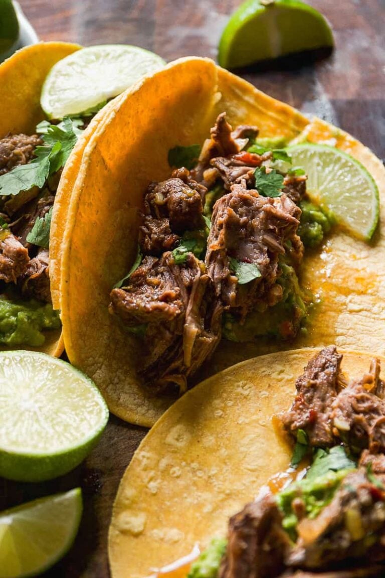 Close image of barbacoa tacos topped with lime and cilantro.