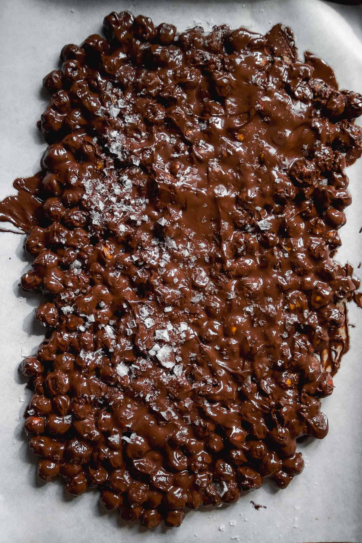 Chocolate chickpeas spread out on a pan into bark.