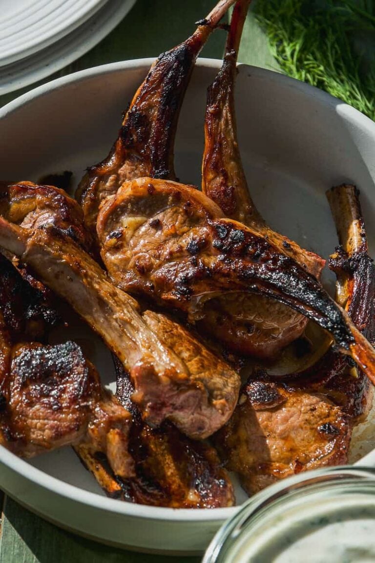 Dish full of lamb lollipops with yogurt dill sauce.