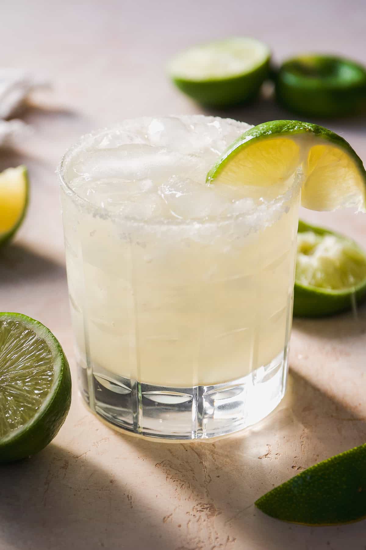 Glass of margarita with salt and lime wedge.