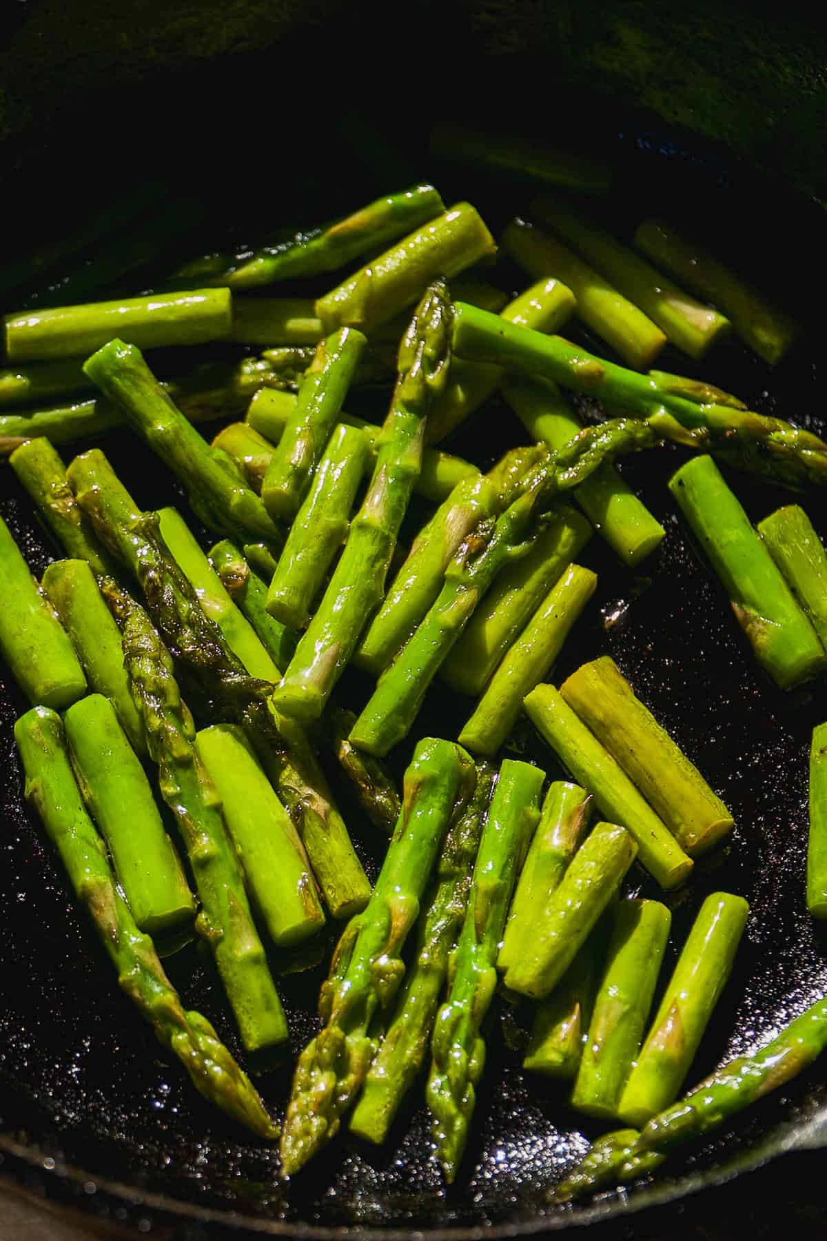 Cooked asparagus in a cast iron skillet.