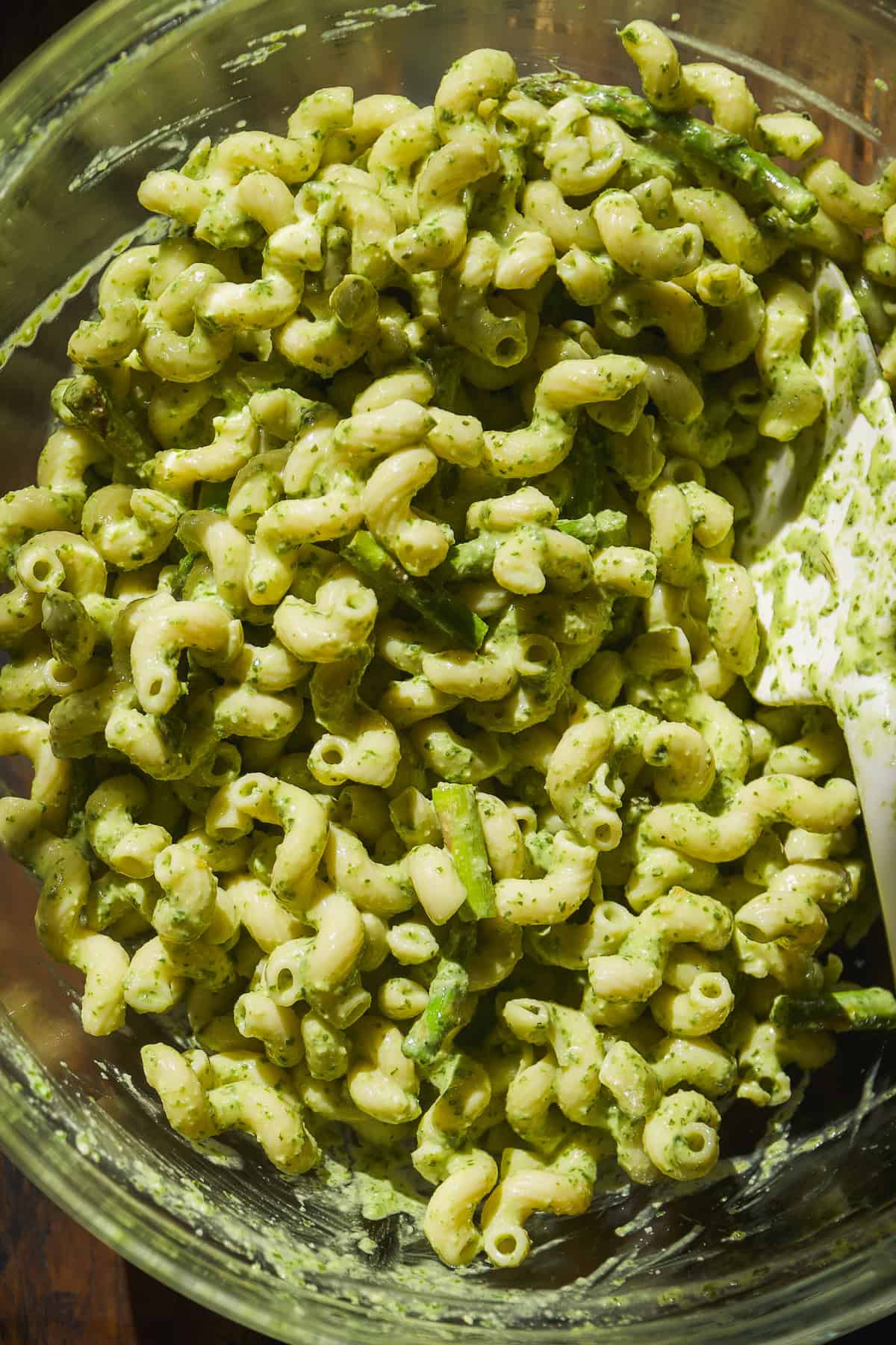 Basil pesto pasta with asparagus in a glass bowl.