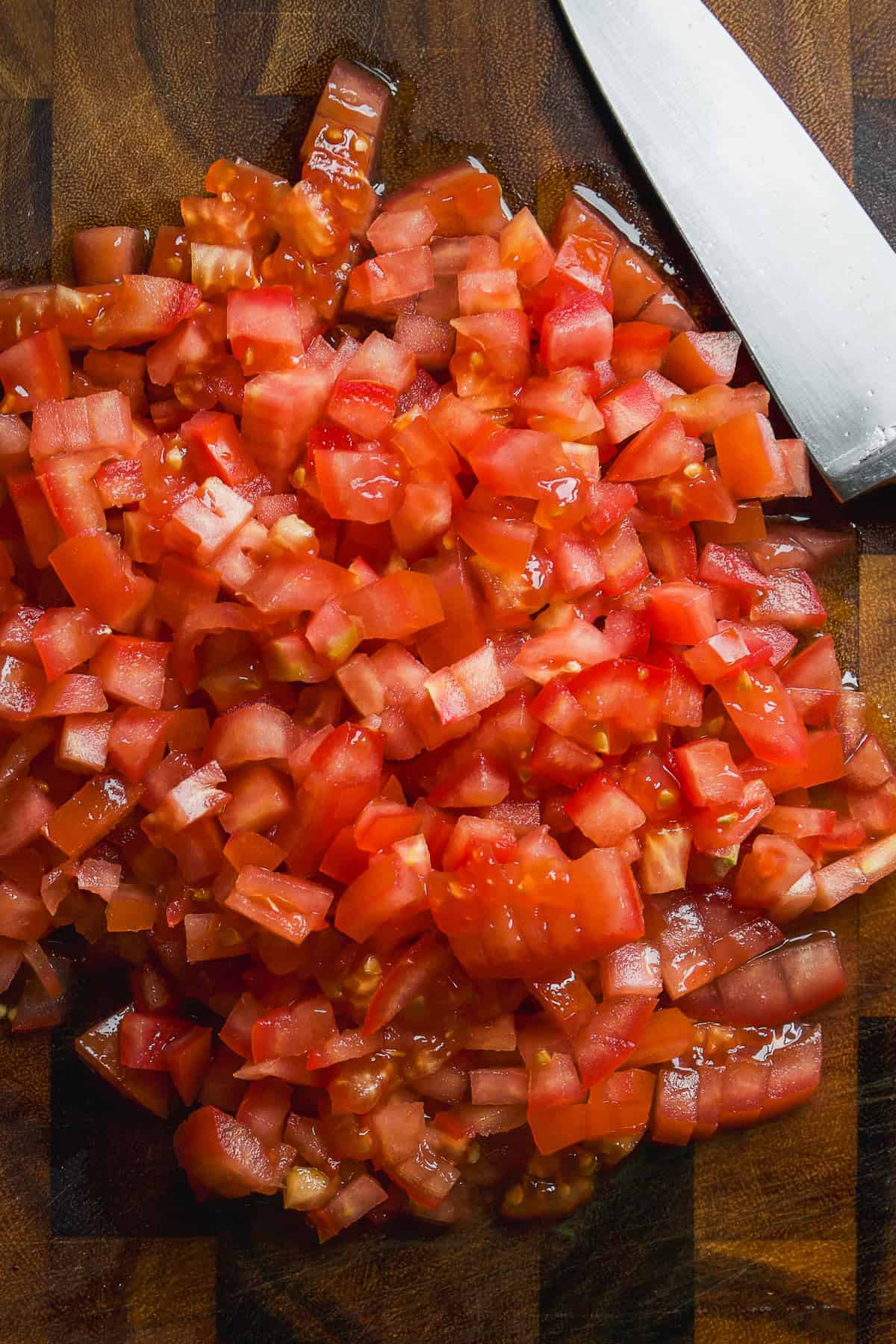 Tomatoes chopped into chunks on a wooden cutting board.