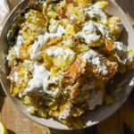 Overhead view of a bowl of smashed potatoes with yogurt sauce.