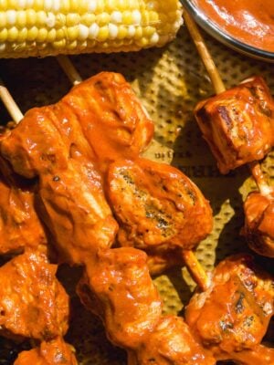 Bbq chicken skewers on a pan with corn.