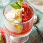Frozen watermelon in a glass jar with yogurt and mint on top.